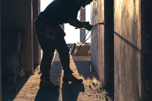 A construction electrician cuts a voltage cable during a repair, silhouette in the light of the setting sun.